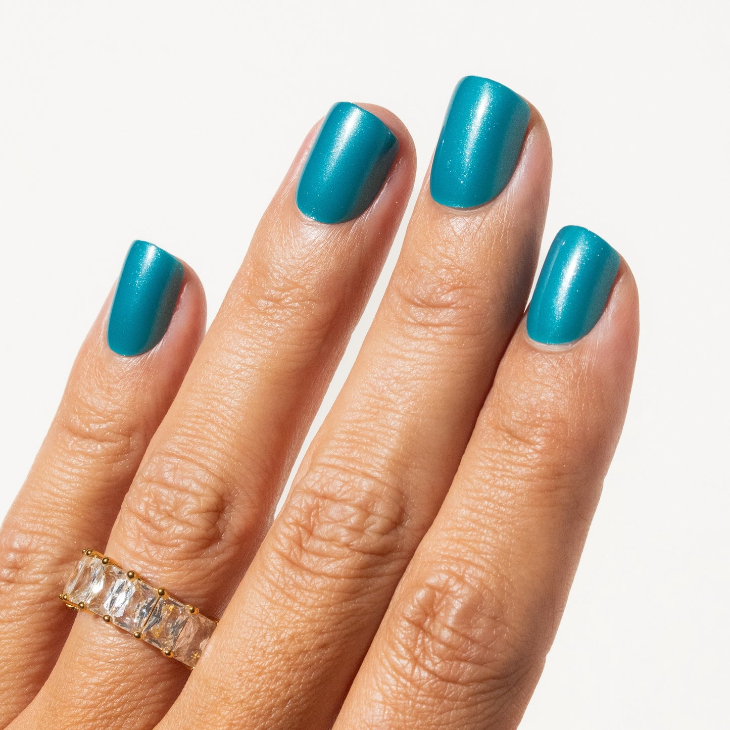 Hand with teal press on nails on a light background