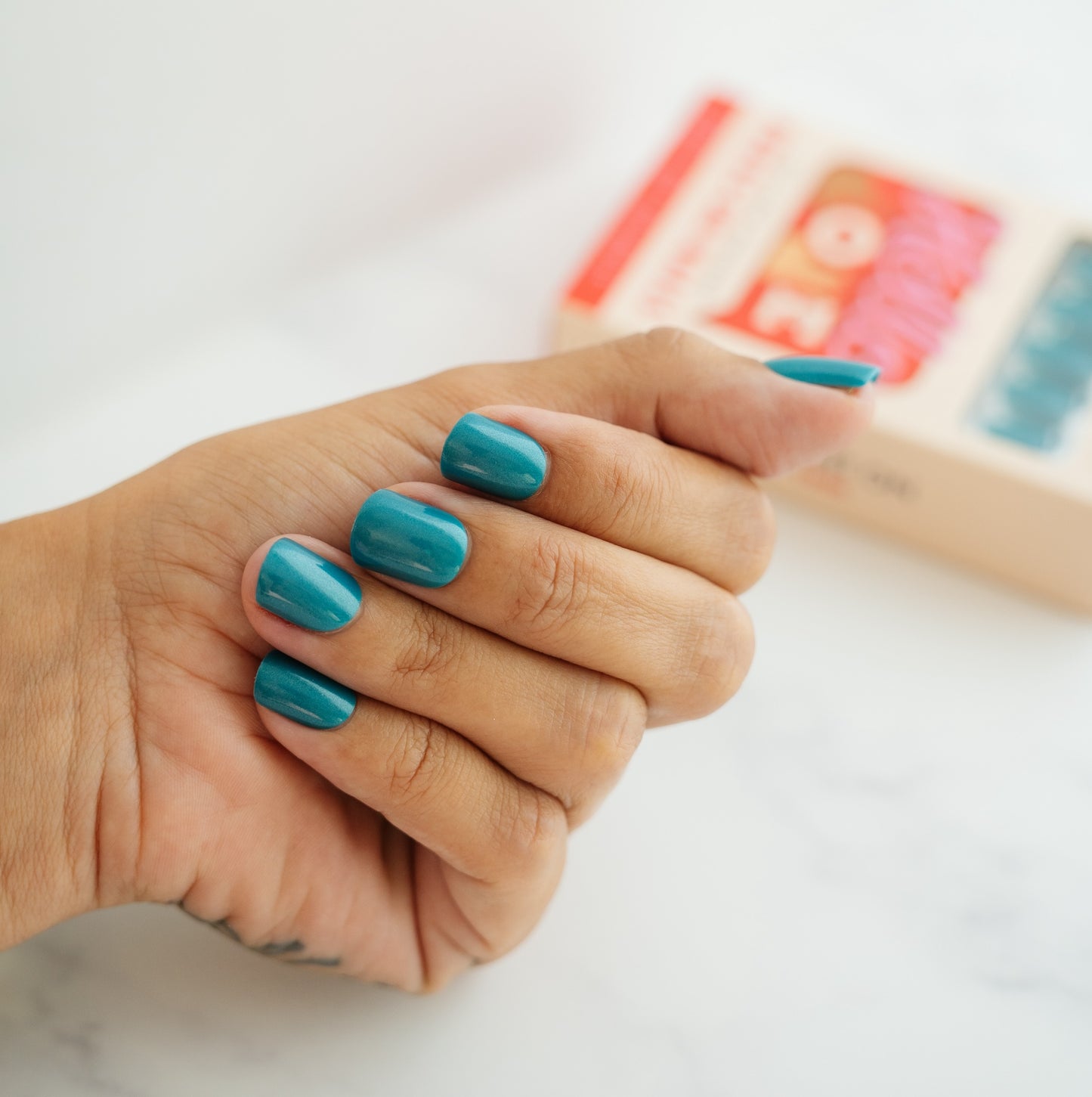 Hand with turquoise press on nails on a white background