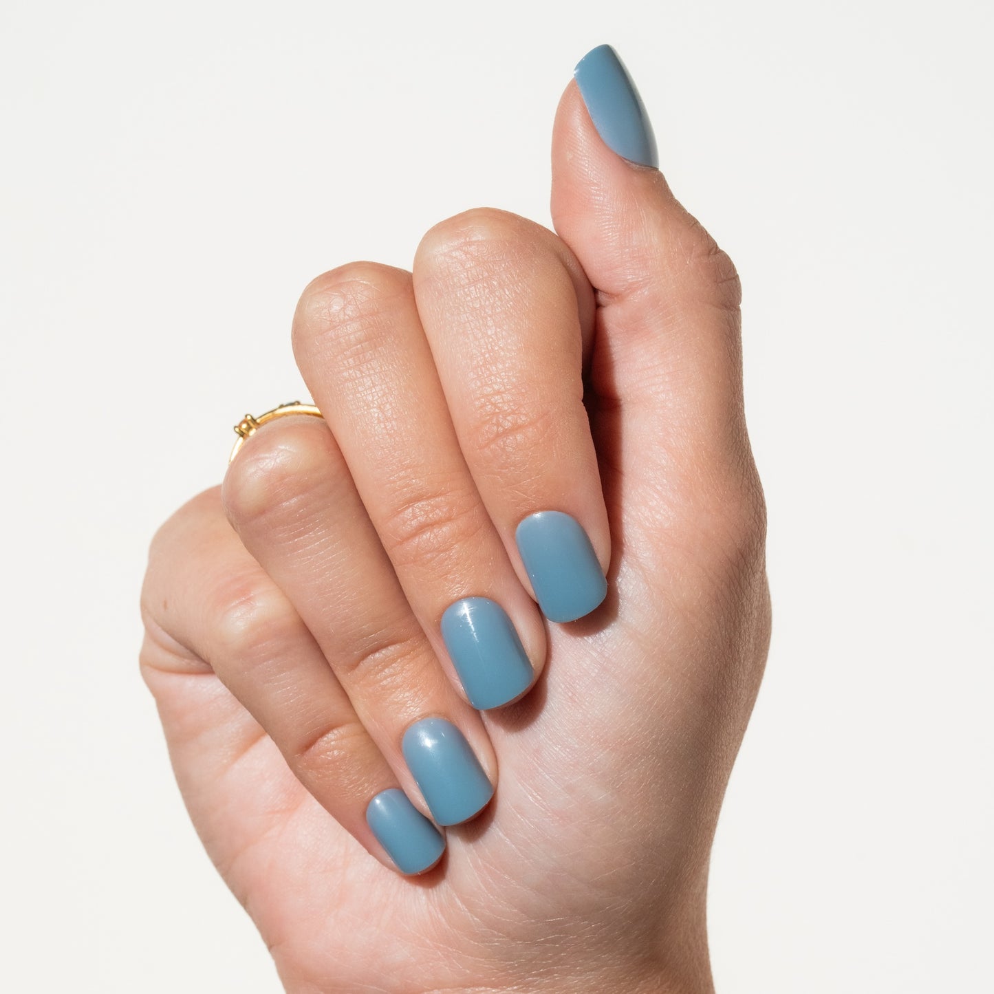 Hand with light blue press on nails on a plain background