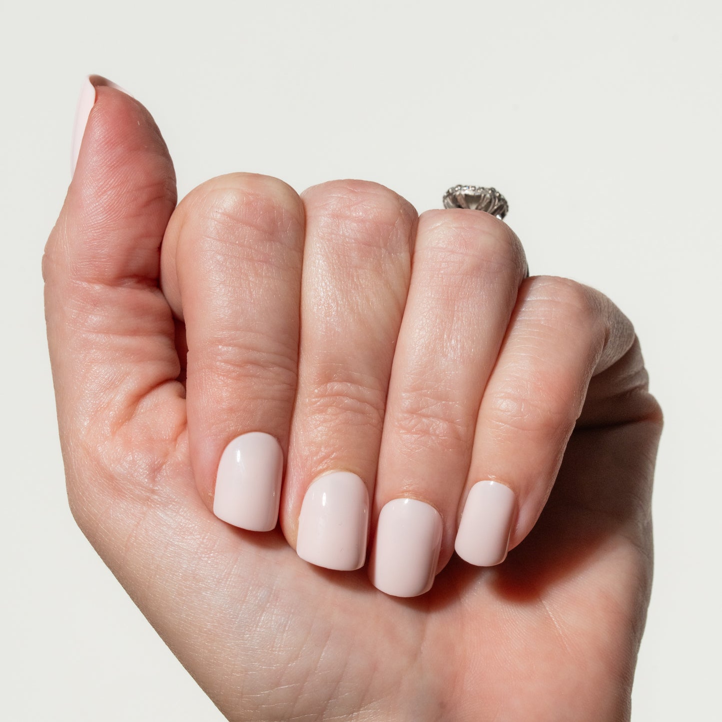 Hand with light pink nail press on nails on a neutral background