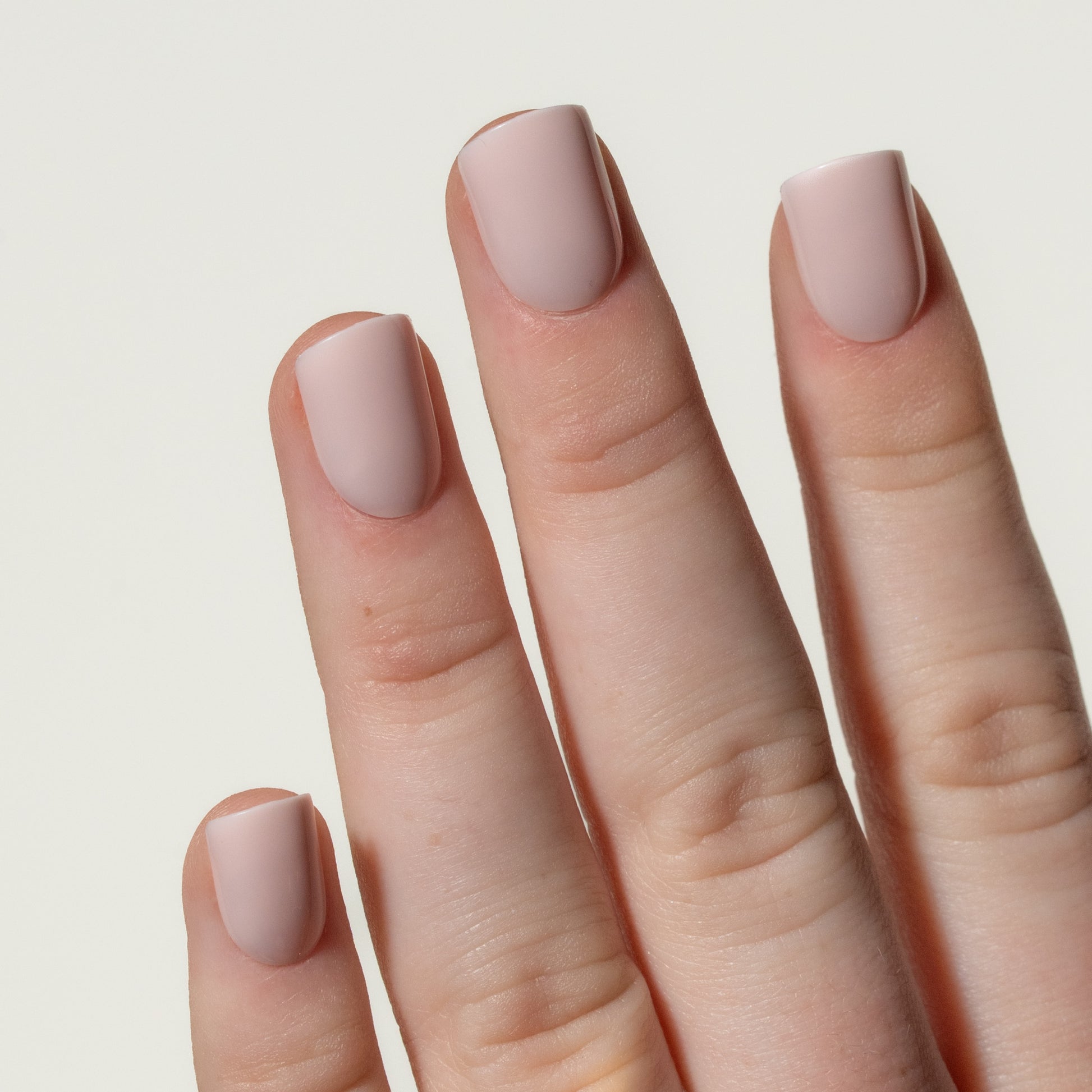 Hand with light pink press on nails on a neutral background