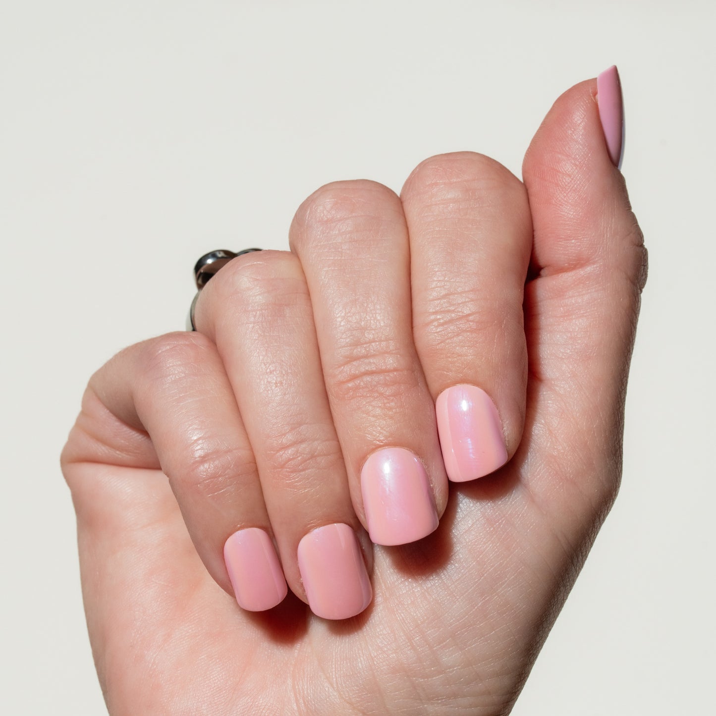 Hand with pink press on nails on a plain background
