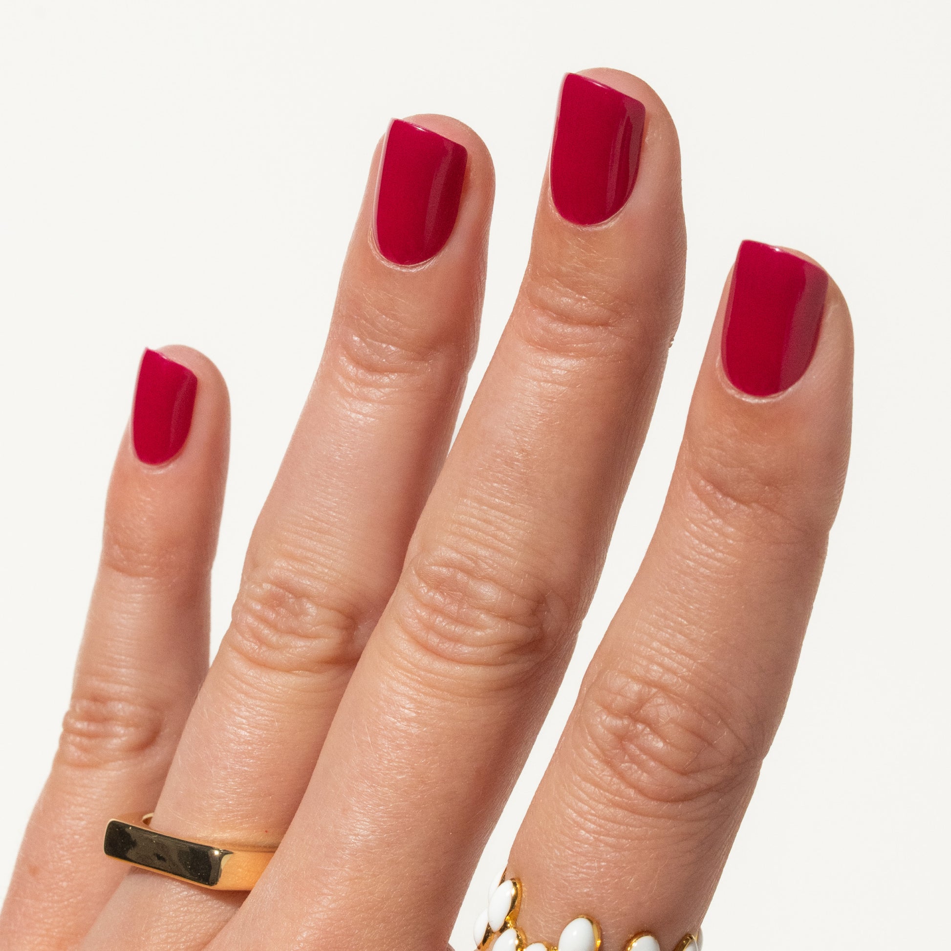 Hand with berry pink press ons on a white background