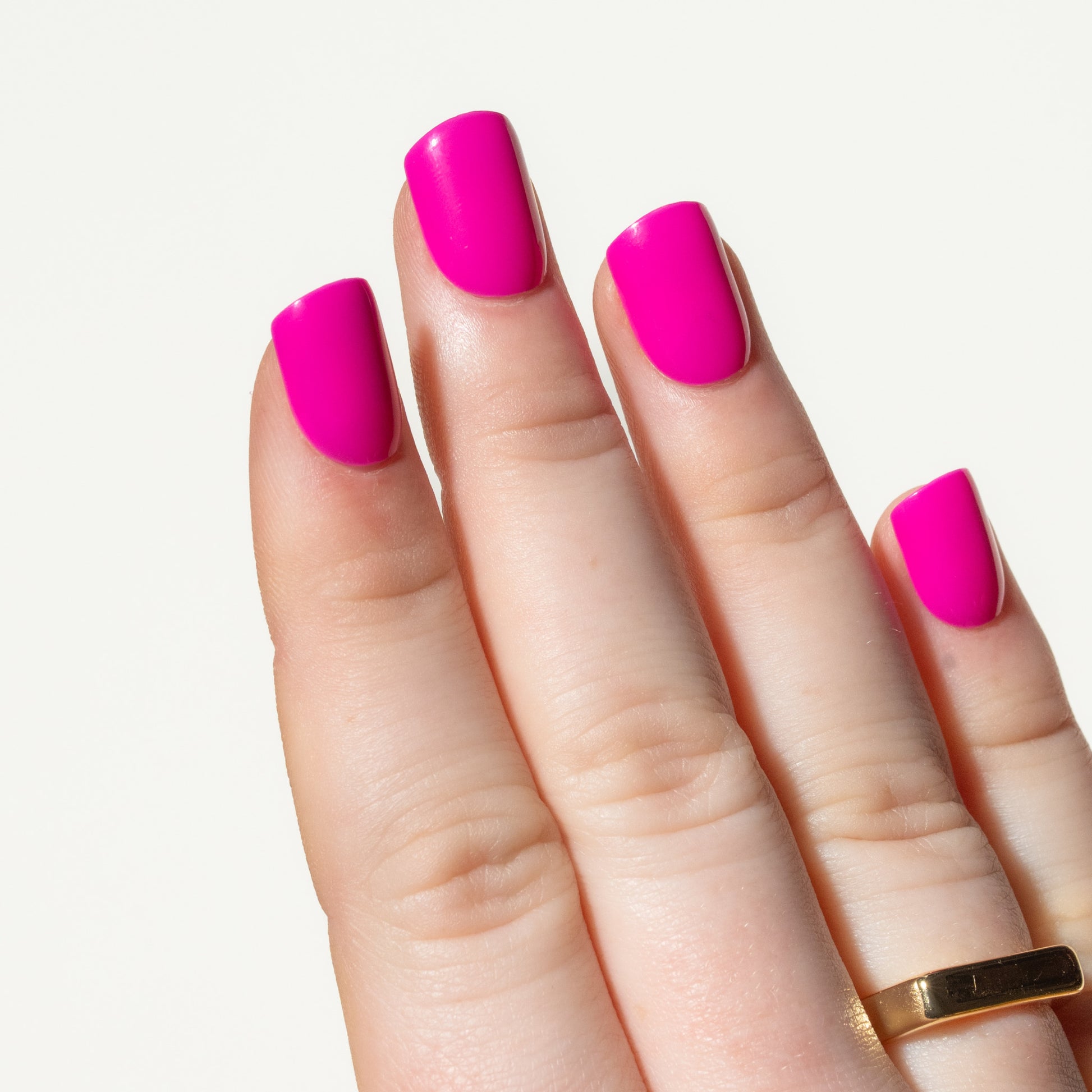 Hand with bright pink press on nails on a light background