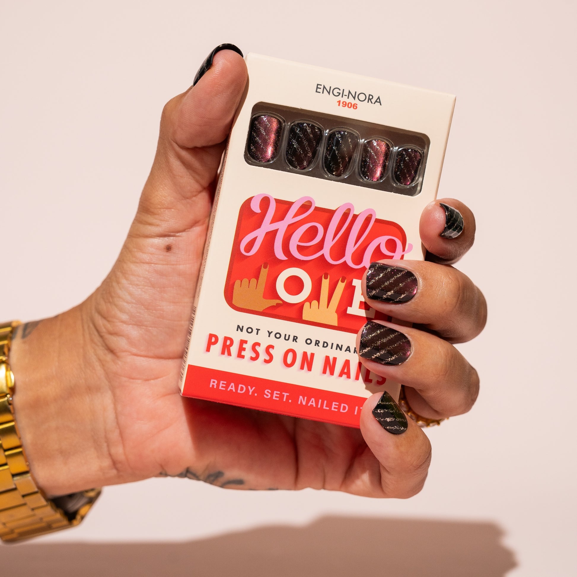 Hand holding a box of press-on nails with 'Hello Love' branding.