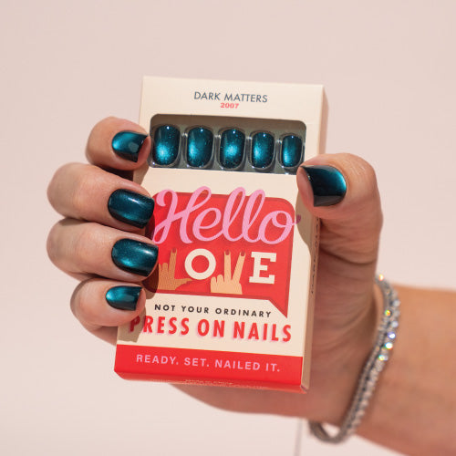 Hand holding a box of press-on nails with Hello Love branding