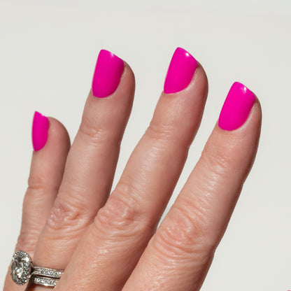 Hand with bright pink nails on a plain background