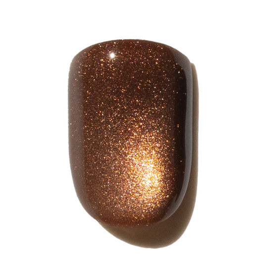 Press on nail with glittery brown finish on a white background