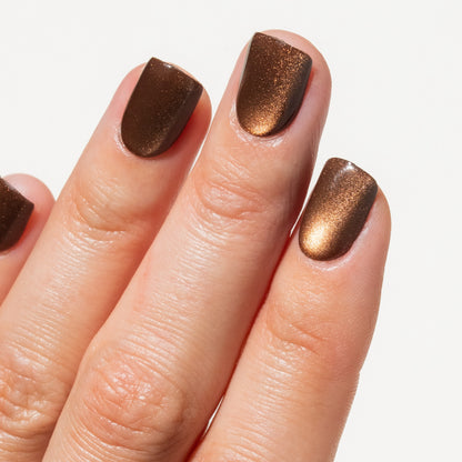 Close-up of a hand with brown press on nails on a white background