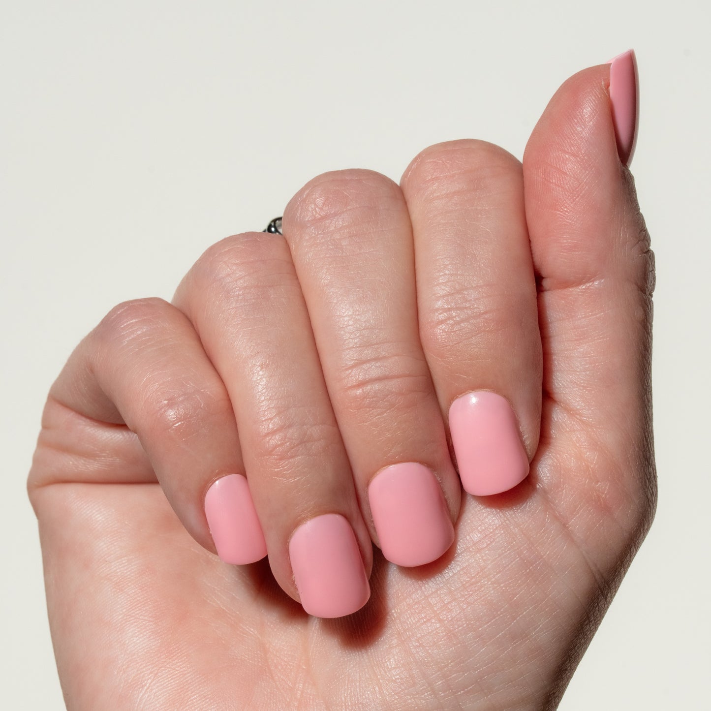 Hand with pink press on nails on a plain background
