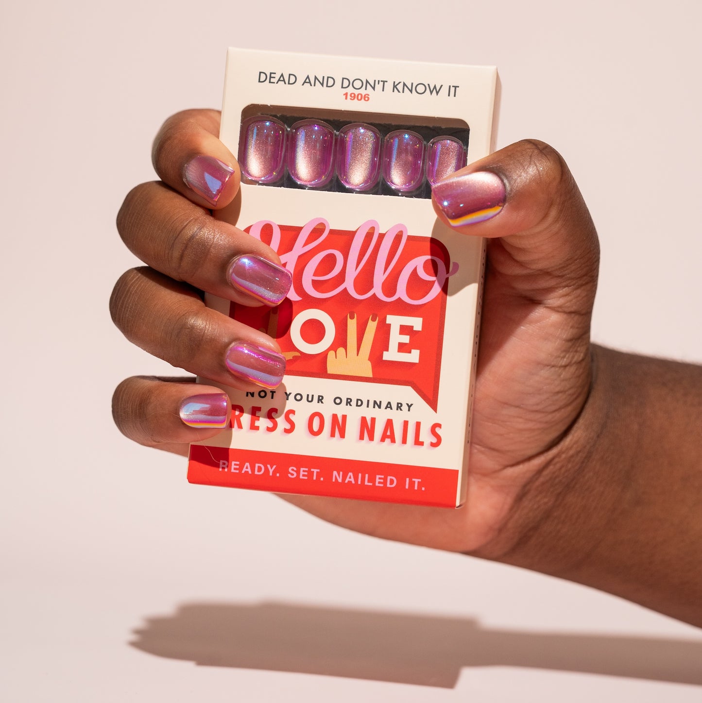 Hand holding a box of cat's eye pink press-on nails