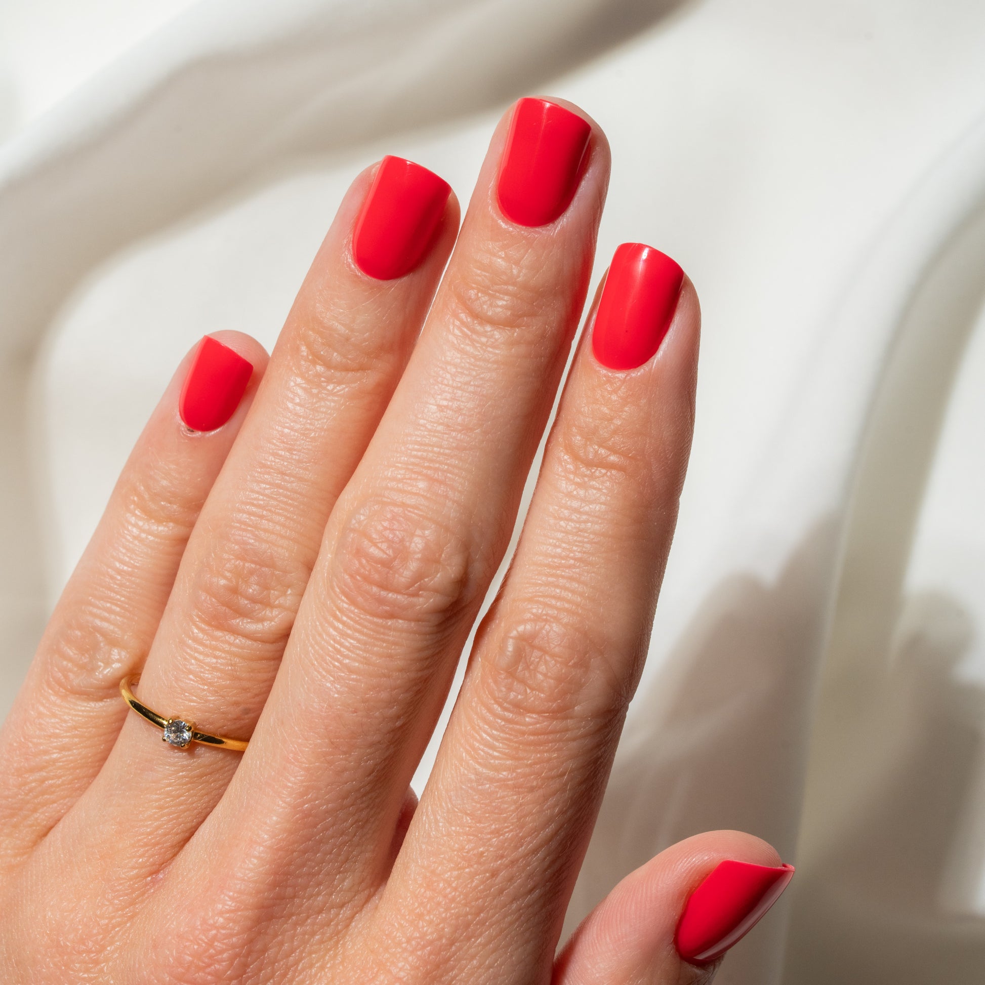 Hand with red press on nails on a neutral background
