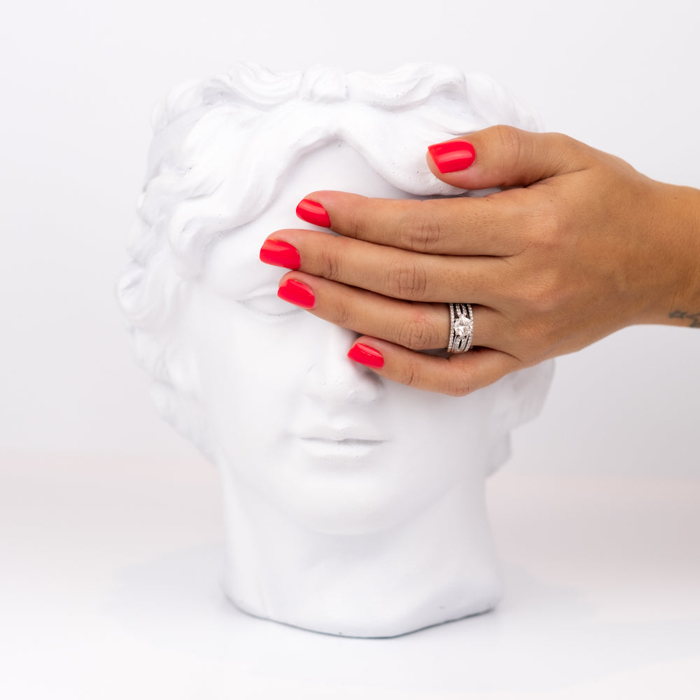 Hand with red press on nails holding a white fabric against a white background
