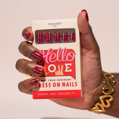 Hand holding a box of press on nails with red Christmas plaid design