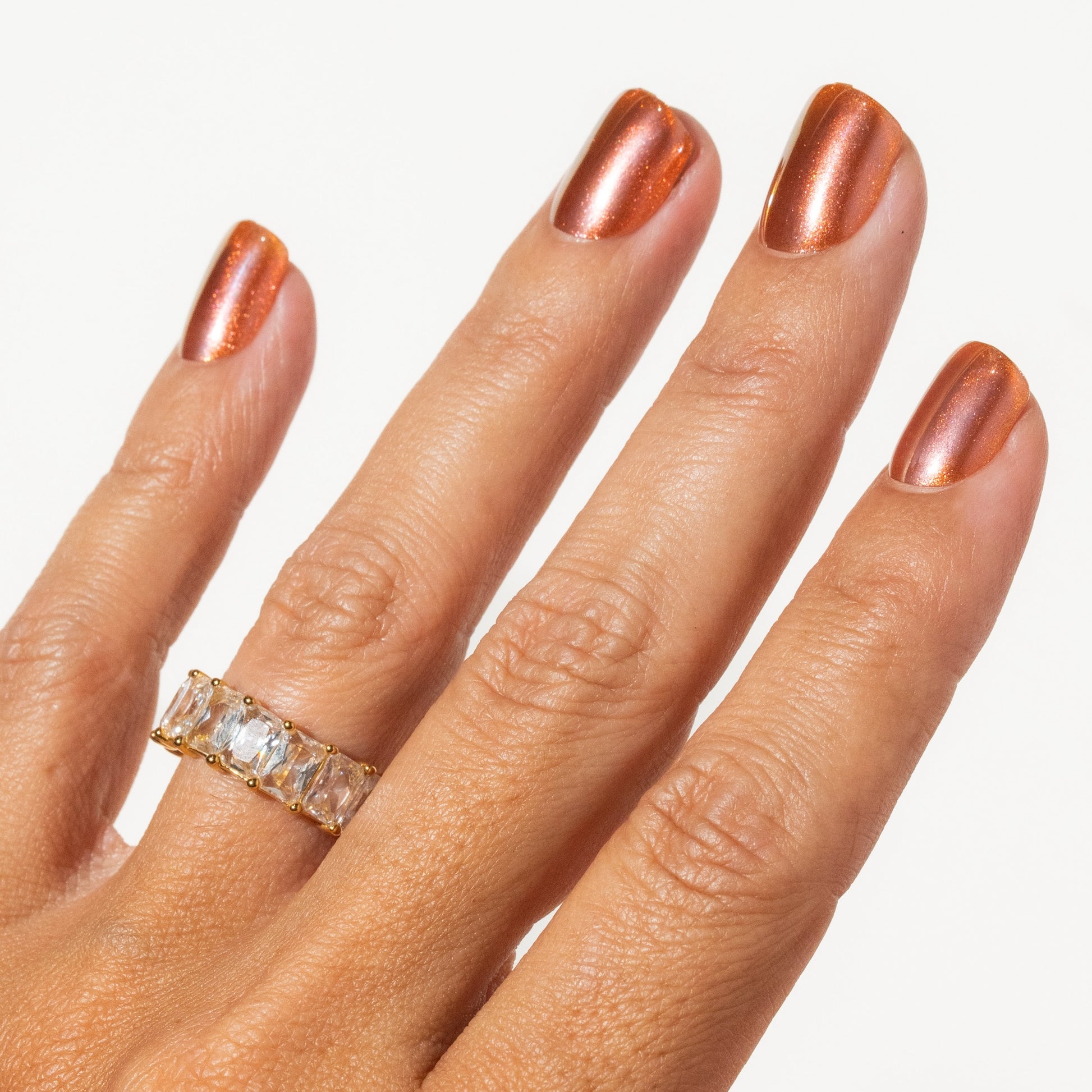 Hand with a ring and rose gold press on nails on a white background