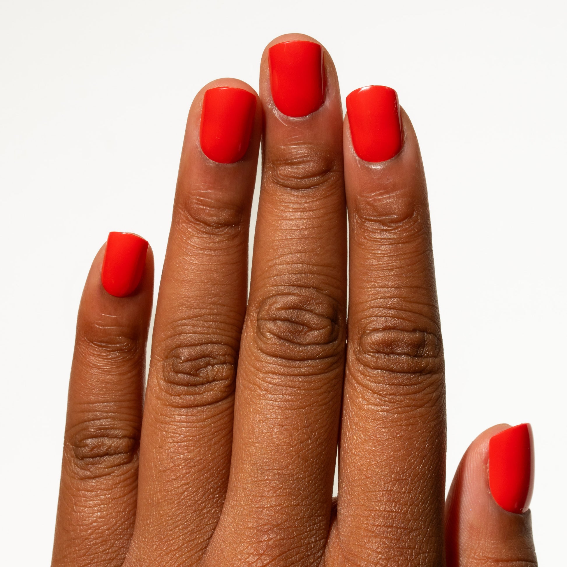 Close-up of a hand with red nails on a white background