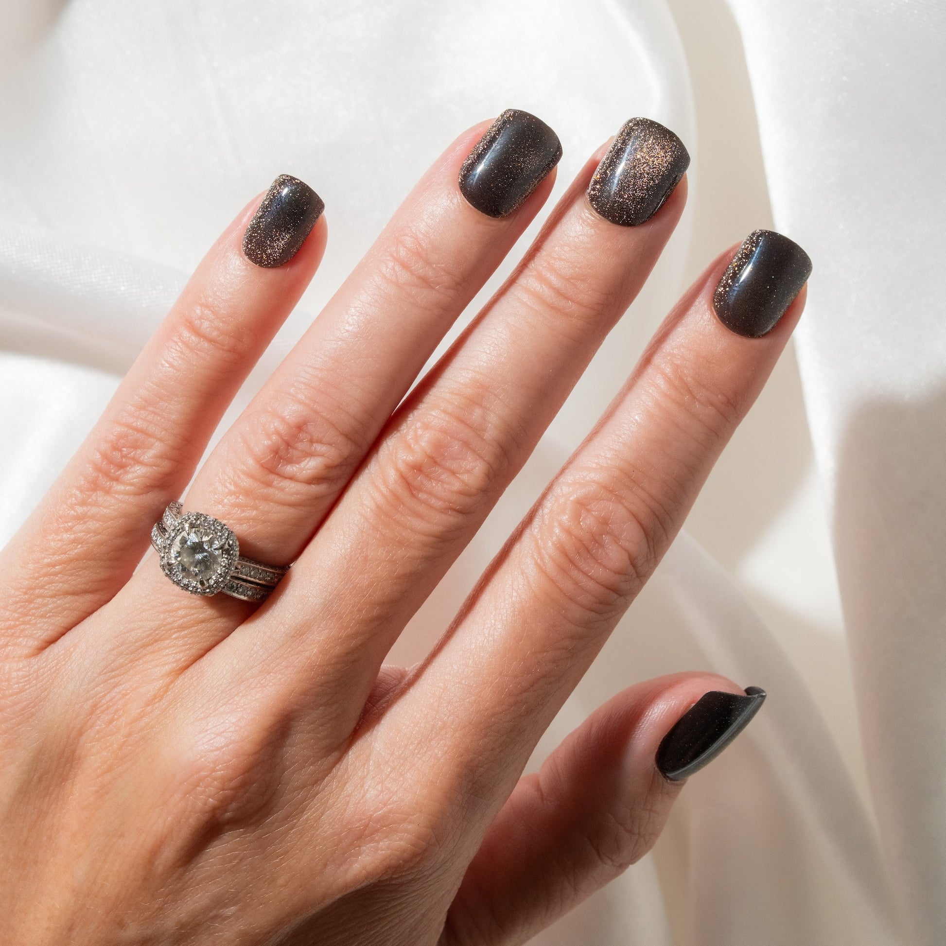 Hand with dark press on nails and a ring on a white background