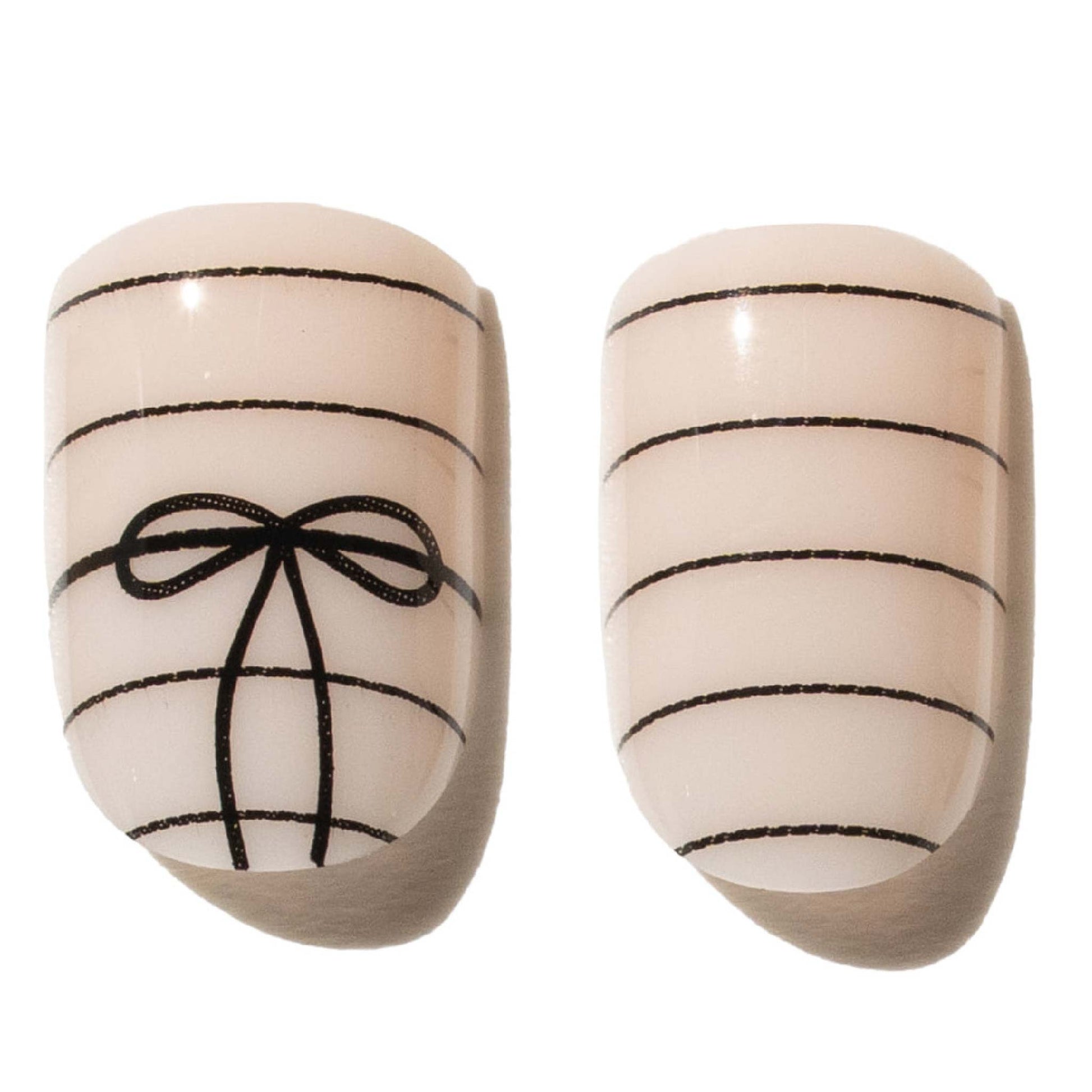 Pair of beige press on nails with black bow design on a white background