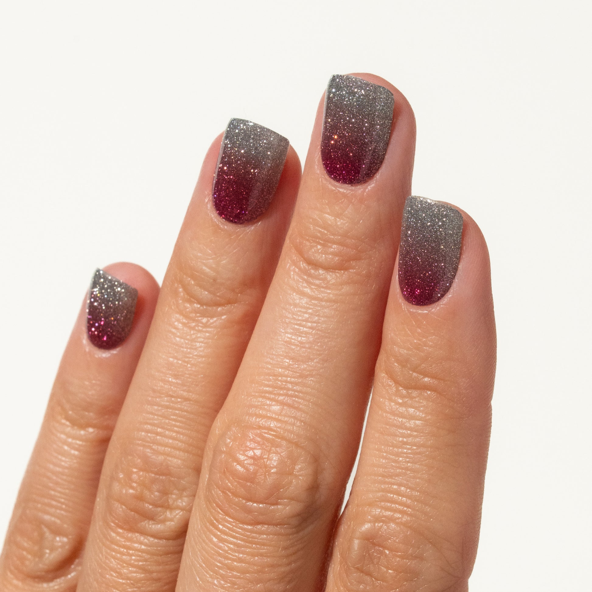 Close-up of a hand with glittery press on nails on a white background