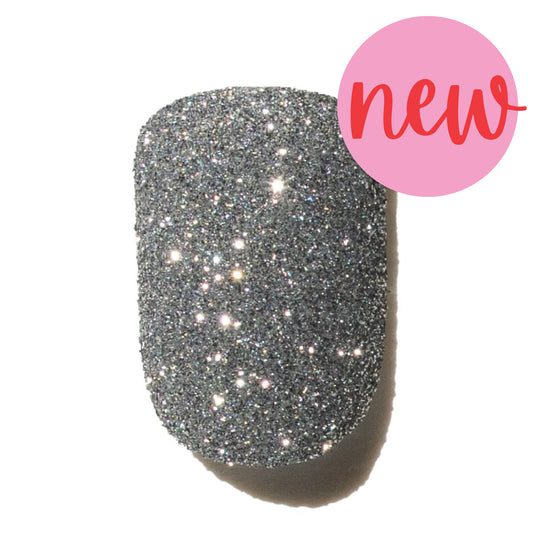 Silver glittery nail polish with a pink 'new' label on a white background