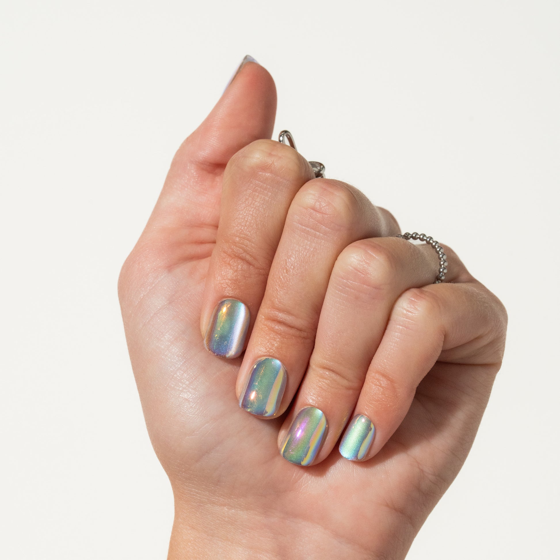 Hand with iridescent press on nails on a plain background