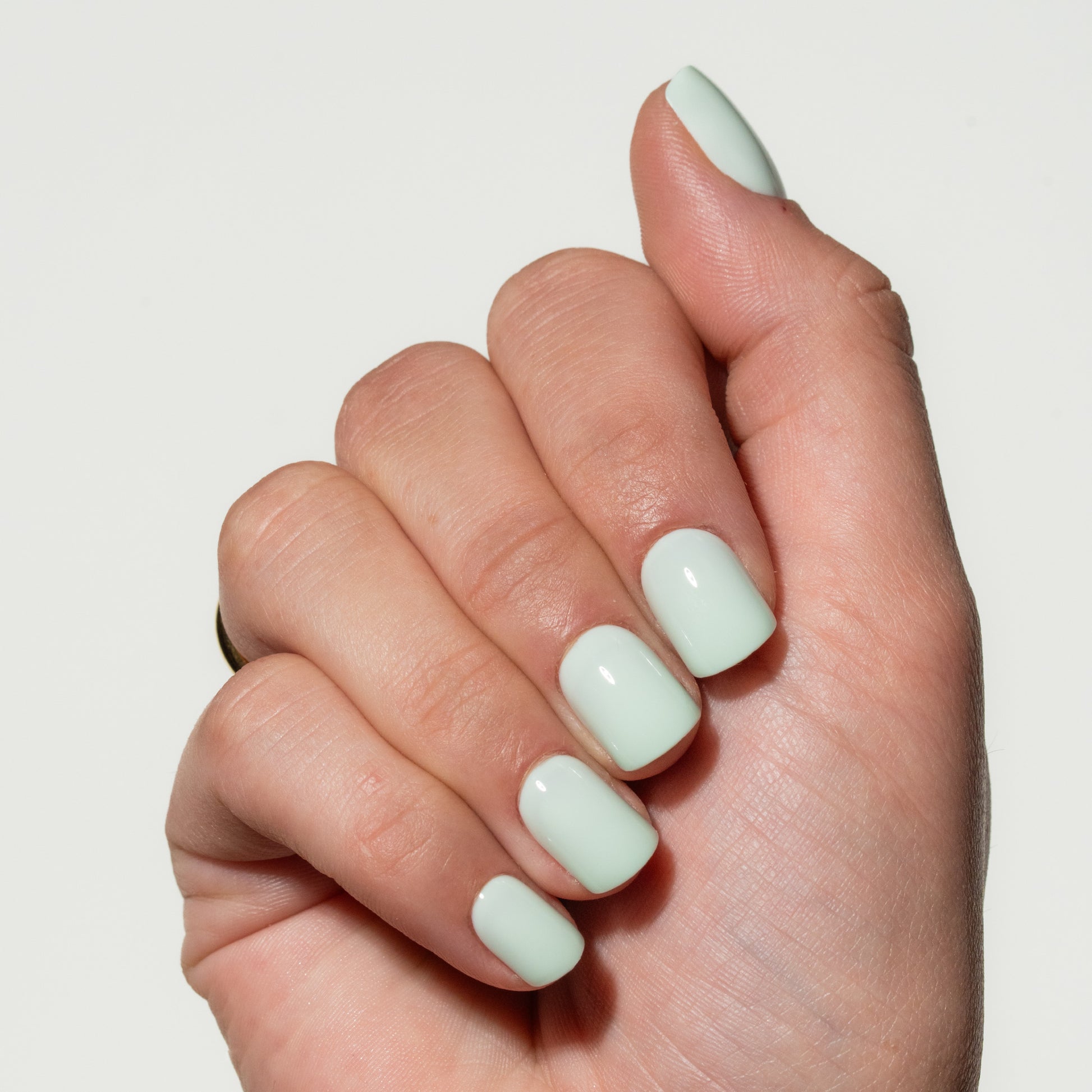 Hand with light green press on nails on a plain background