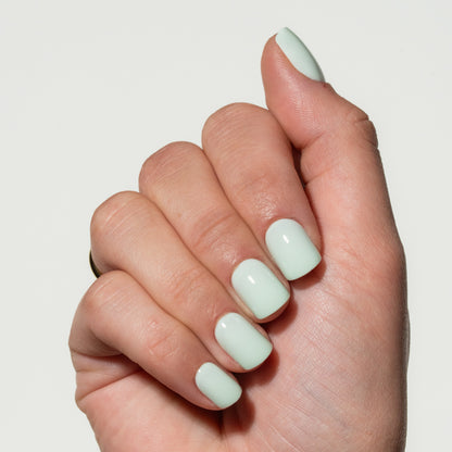 Hand with light green press on nails on a plain background