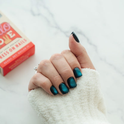 Hand with teal press on nails with a red box in the background.