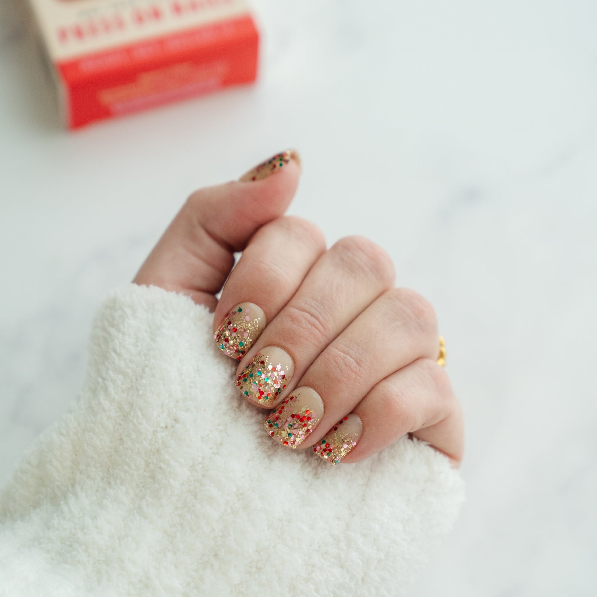 Hand with glittery press on nails on a white background