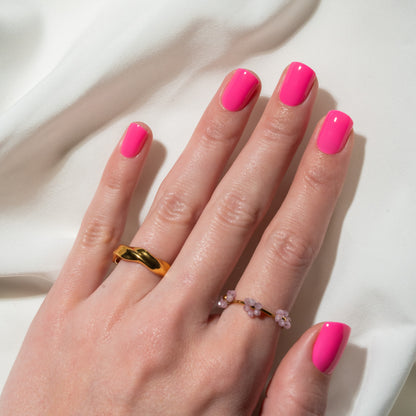Hand with pink press on nails and gold rings on a white background