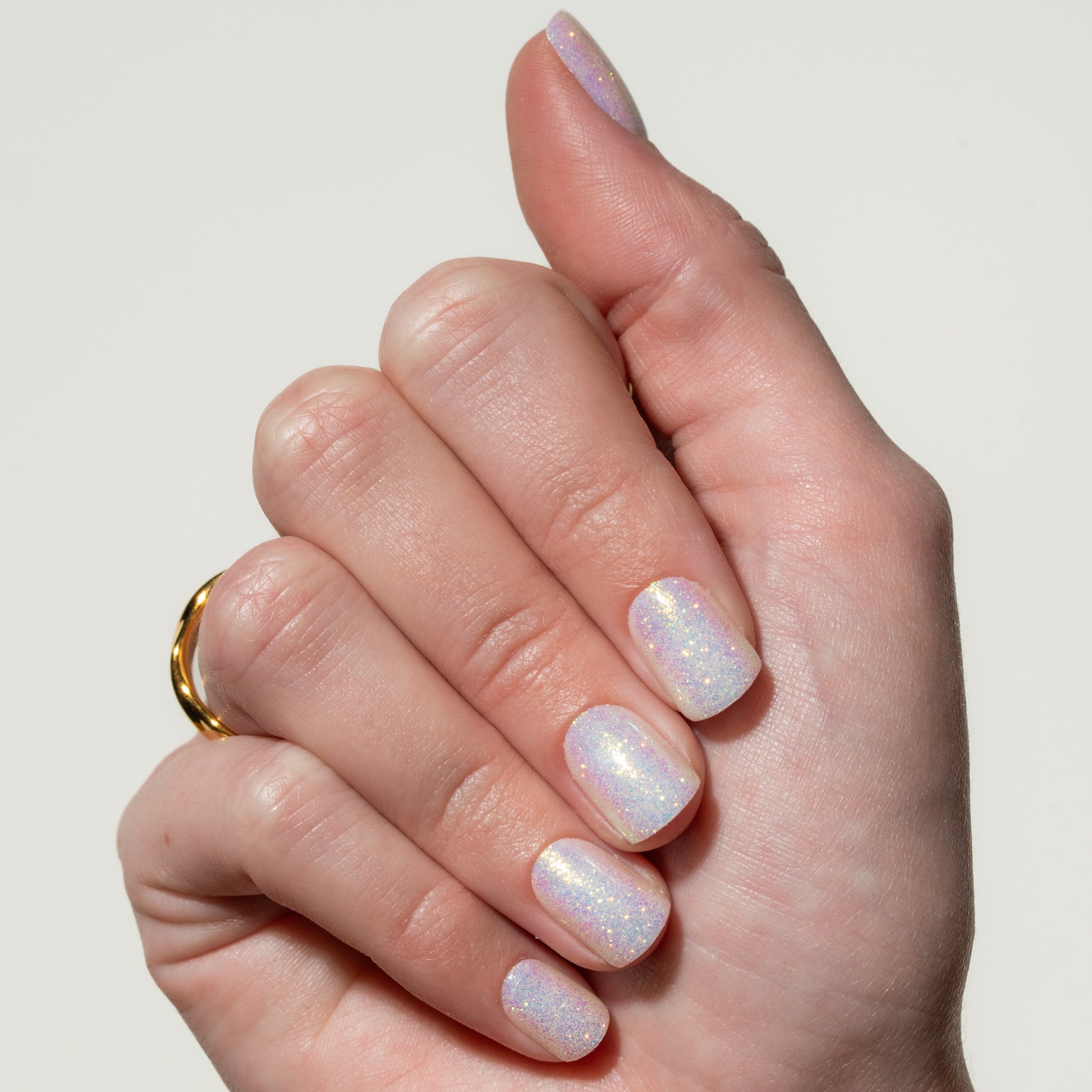 Hand with iridescent press on nails on a plain background