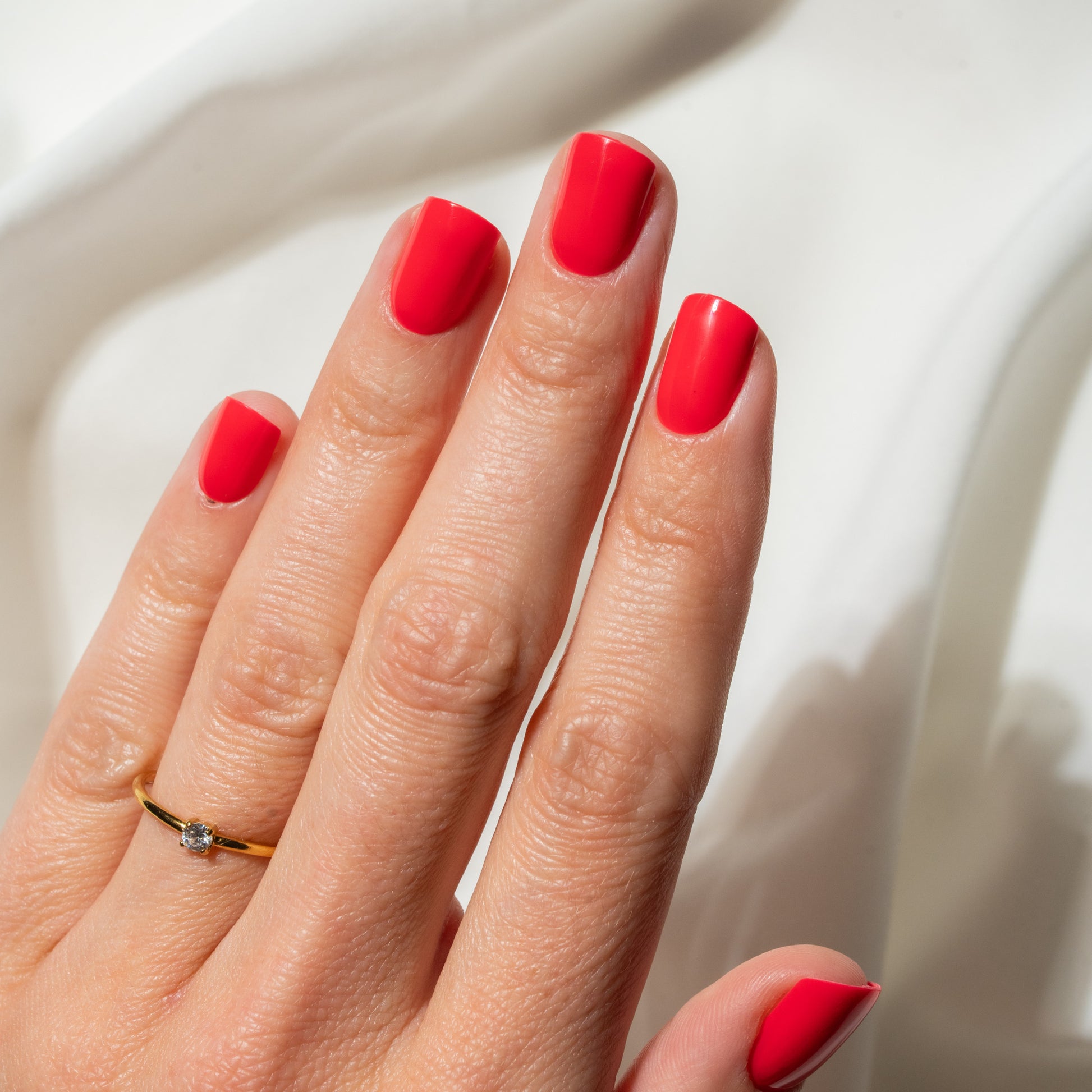 Hand with red press on nails on a neutral background