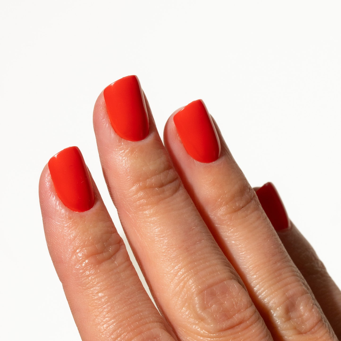 Close-up of a hand with bright red press on nails on a white background
