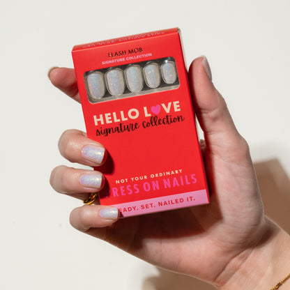 Hand holding a red box of 'Hello Love' press-on nails with a white background