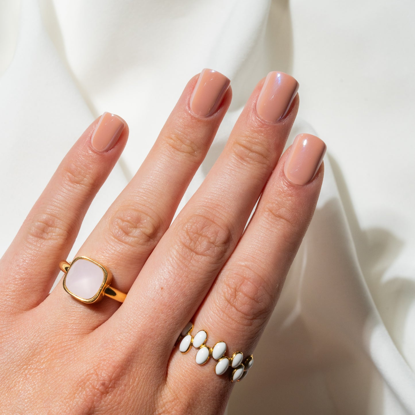 Hand wearing two rings with a soft white background