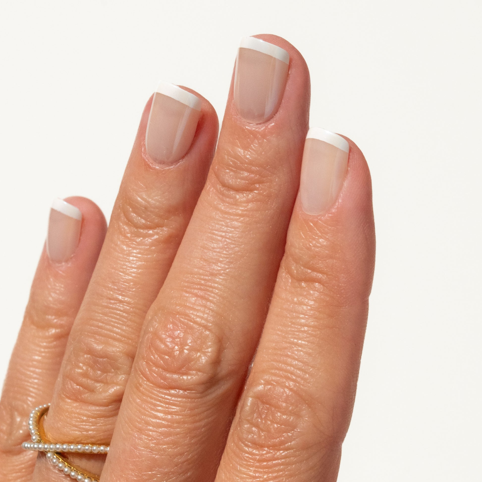 Close-up of a hand with french tip press ons on a white background