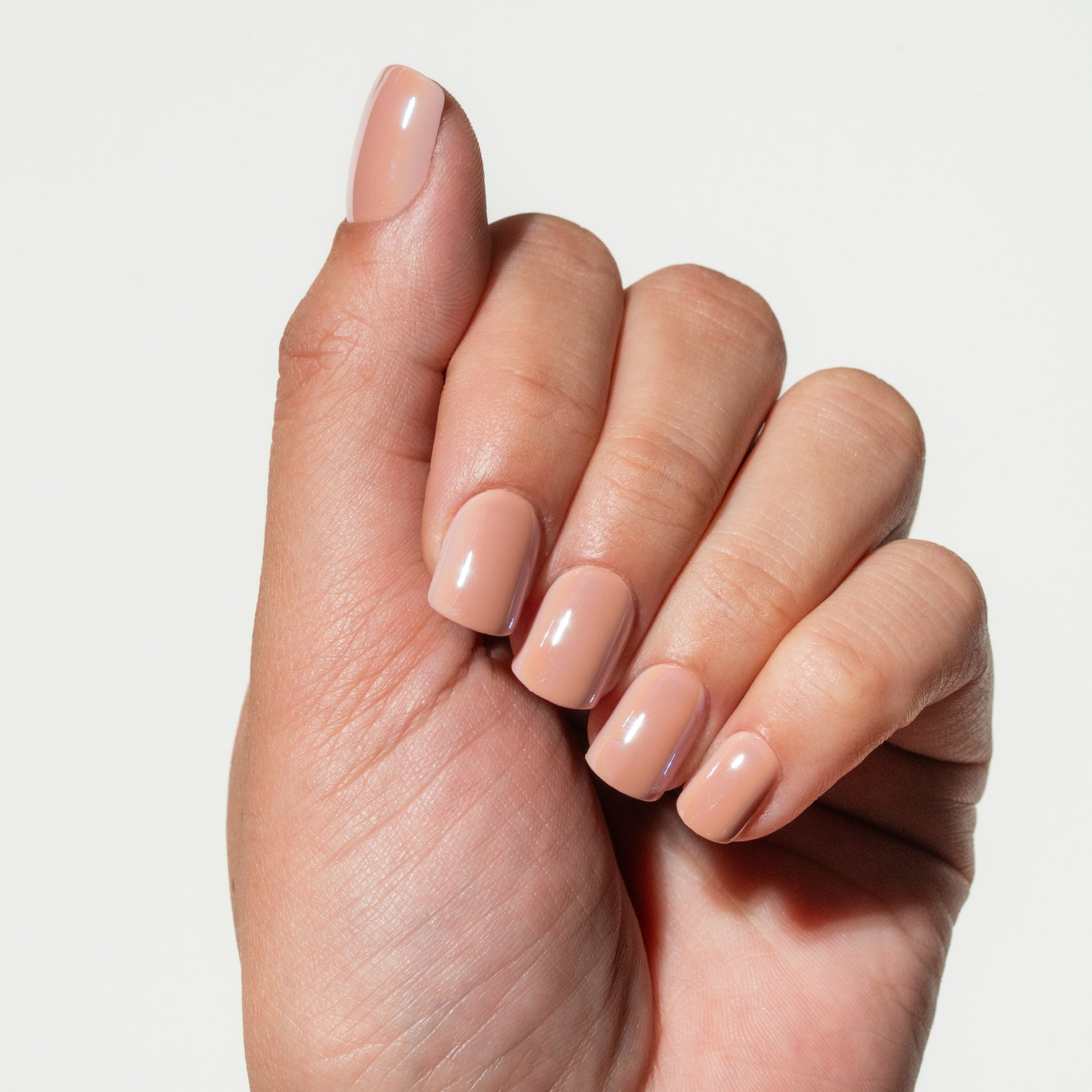Hand with neatly manicured nails on a plain background