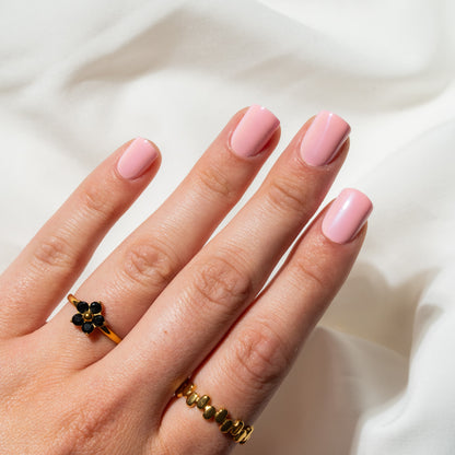 Hand with pink nails wearing two rings on a white background
