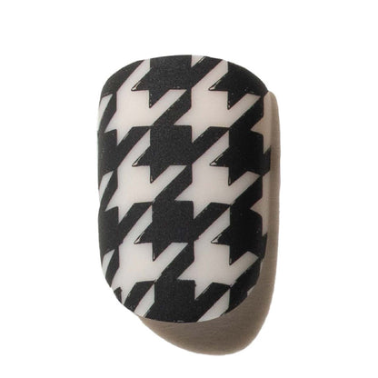 Black and white houndstooth press on nail object on a beige background