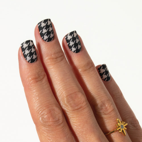 Hand with houndstooth patterned press on nails on a white background