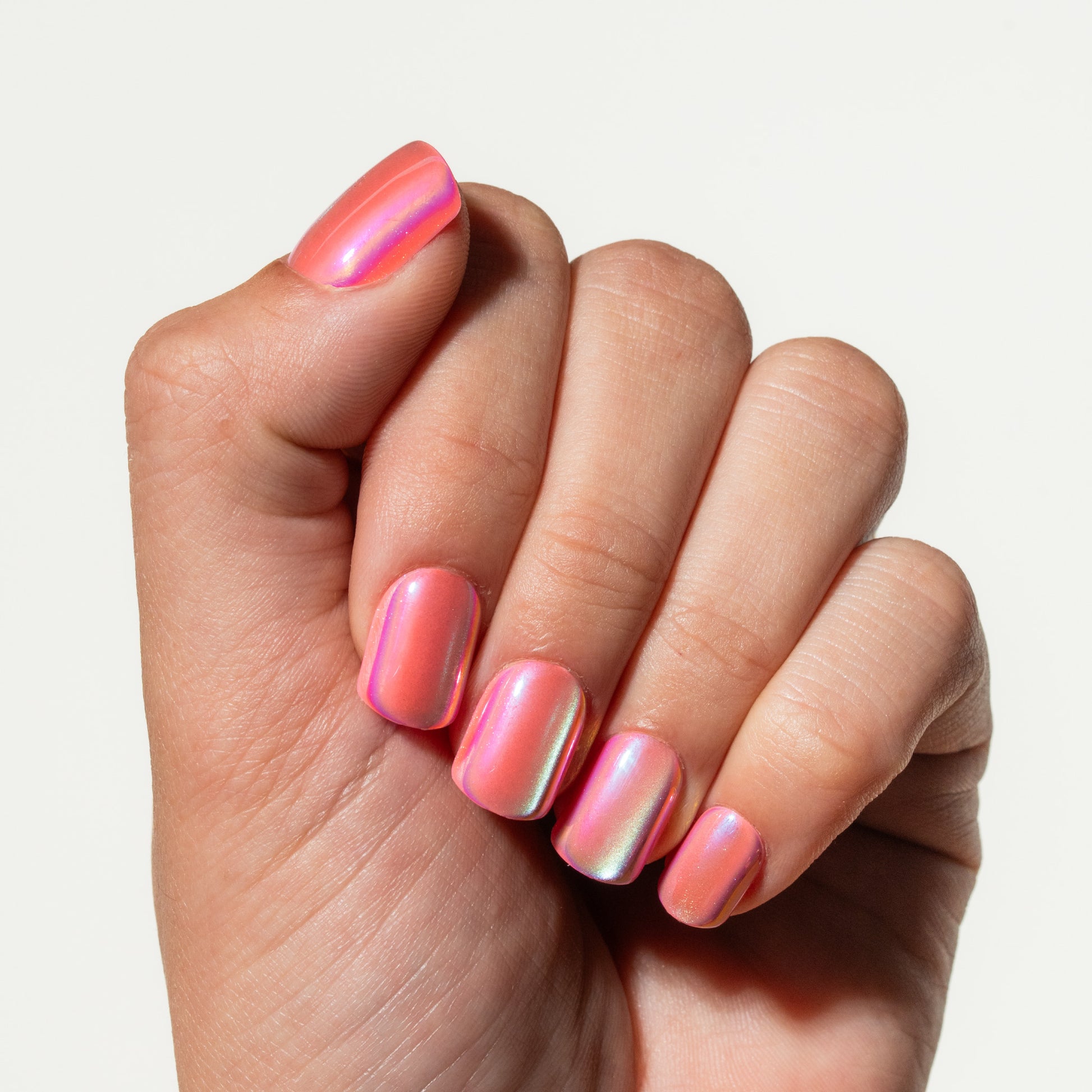Hand with pink and silver press on nails on a light background