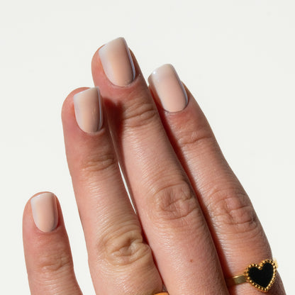 Close-up of a hand with beige press on nails on a light gray background