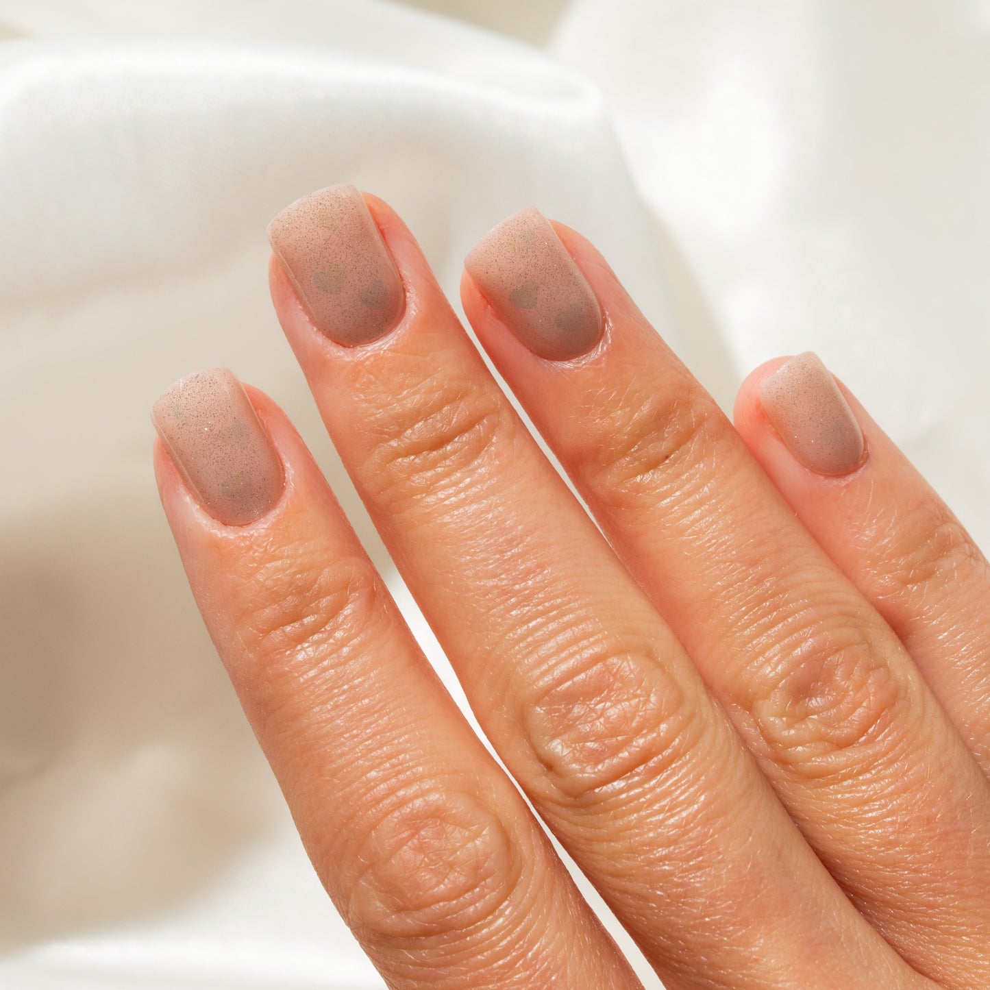 Close-up of a hand with press on nails on a white background