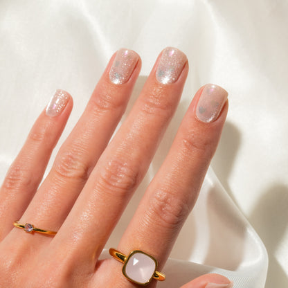 Hand with glittery press on nails and gold rings on a white background