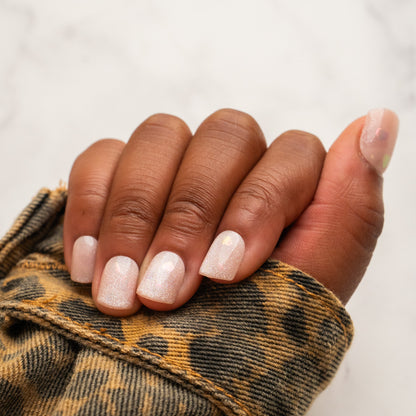 Close-up of a hand with light pink press on nails wearing a leopard print sleeve.