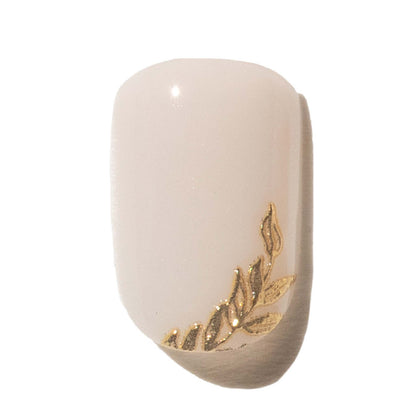 Press on nail with gold leaf design on a white background