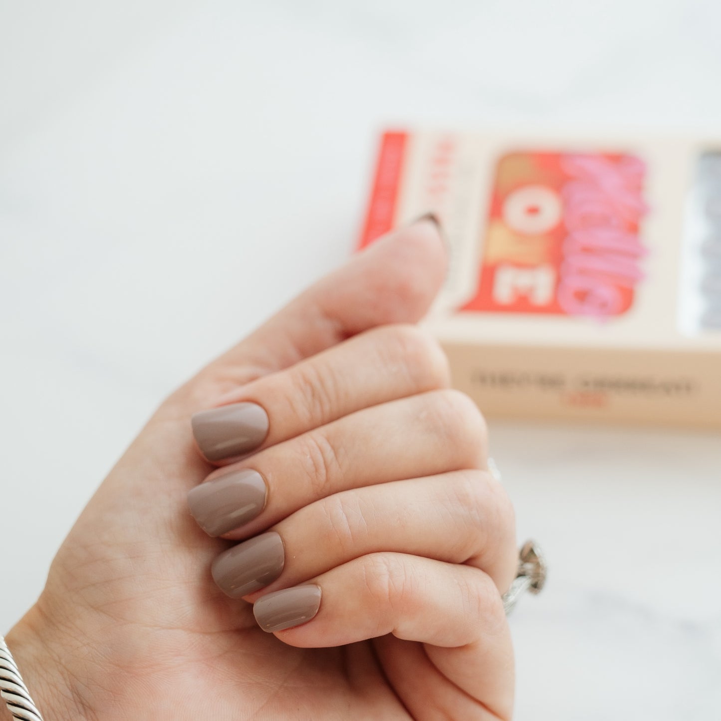 Hand with light brown press on nails on a white background