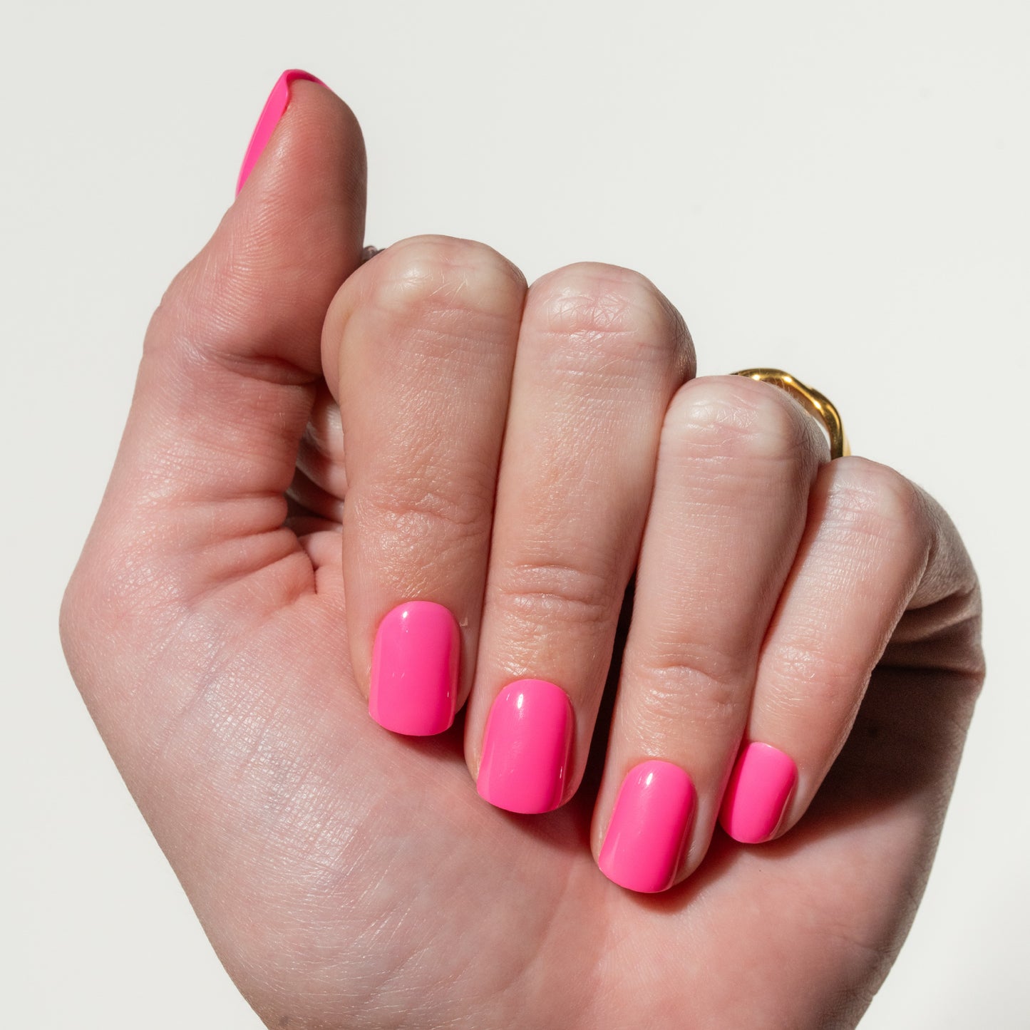 Hand with bright pink press on nails on a plain background