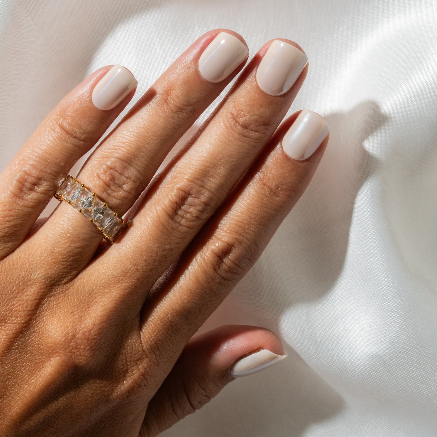 Hand with off white press on nails on a light background