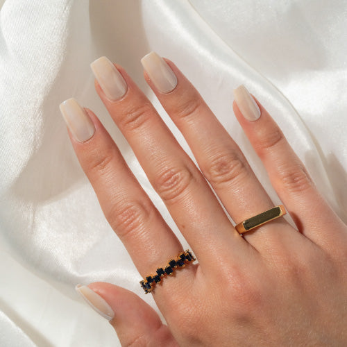 Hand wearing two rings on a white fabric background